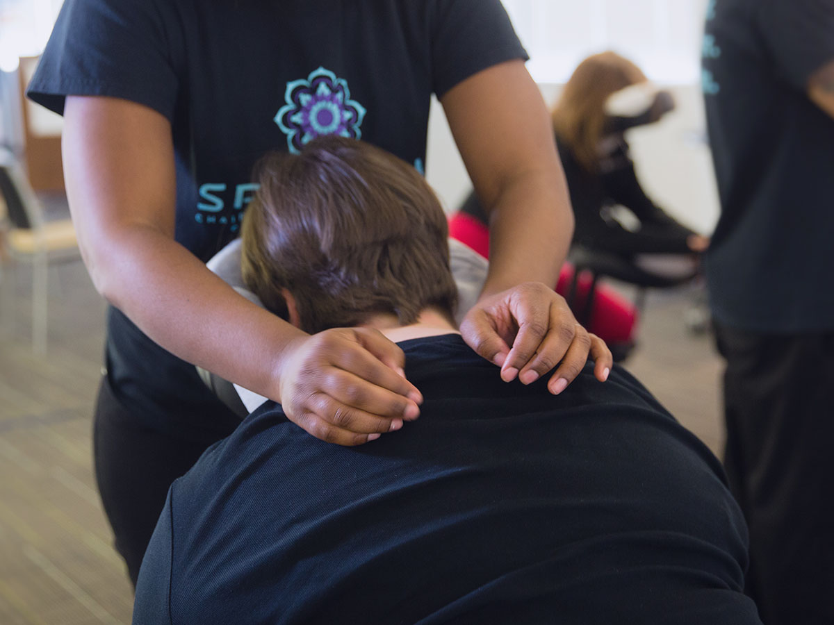 Spa Flow employee doing chair massages at a convention